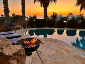 een grill met hotdogs naast een zwembad bij Sky Villa in Paphos City