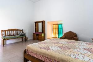 ein Schlafzimmer mit einem Bett, einem Stuhl und einem Fenster in der Unterkunft Dragonfly Guest House in Sucre