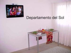 een tafel in een kamer met een tv aan de muur bij Departamentos del Sol in Necochea