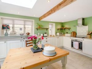 a kitchen with white cabinets and a wooden table at 1 Chapel Terrace in Ebberston