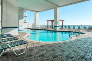 una piscina en un edificio con sillas y el océano en Majestic Beach Towers 1-1701, en Panama City Beach