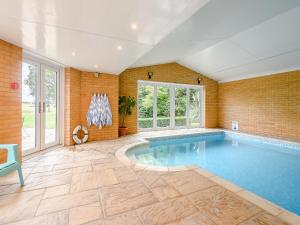 a swimming pool in a room with a brick wall at Cherry Ridge in Great Bircham