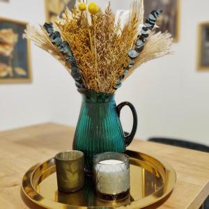 a green vase with flowers and a candle on a table at harmony holiday in Jünkerath