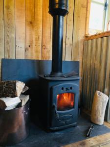 a wood stove in a room with a bucket at The Big Green Shepherds Hut in Charlwood