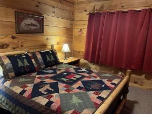 a bedroom with a bed with a quilt on it at Story Brook: Beautiful true log cabin! Close to Dollywood, State Park, and more! in Sevierville