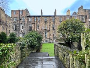 einen Weg, der zu einem großen Backsteingebäude führt in der Unterkunft 2Bed, Private Garden & Fireplace, Near Water of Leith in Edinburgh