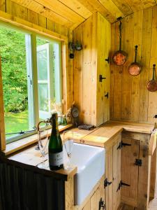 a kitchen with a sink and a bottle of wine at The Big Green Shepherds Hut in Charlwood