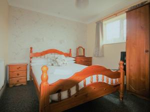 a bedroom with a wooden bed and a window at Tom Putt in Ledbury