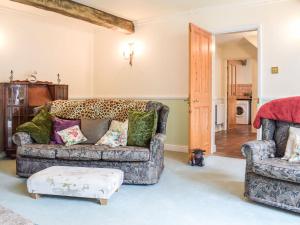 uma sala de estar com um sofá e uma cadeira em Holly Cottage em Lilleshall