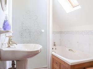 y baño blanco con lavabo y bañera. en Holly Cottage en Lilleshall