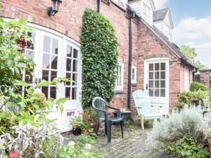 a brick house with two chairs in the garden at Holly Cottage in Lilleshall