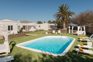 a swimming pool in a yard with chairs and a house at VILLAS NEW LANZASUITES PLUS in Playa Blanca
