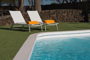 duas cadeiras sentadas ao lado de uma piscina em VILLAS NEW LANZASUITES PLUS em Playa Blanca