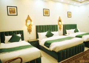 a bedroom with two beds with green and white sheets at Golden One Hotel in Lahore