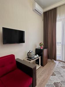 a living room with a red couch and a flat screen tv at Bastau Hotel in Almaty