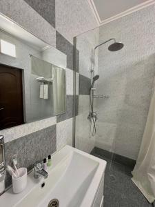 a bathroom with a white sink and a shower at Bastau Hotel in Almaty