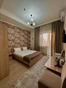 a bedroom with a bed and a couch and a window at Bastau Hotel in Almaty