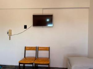 Habitación con 2 sillas y TV en la pared. en Alquiler Temporario Azcuénaga en Morón