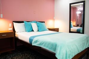 een slaapkamer met een groot bed met blauwe kussens bij Hotel Brisas De Calima in Cali