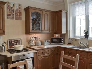 a kitchen with wooden cabinets and a stove top oven at Ashlea in Teversall