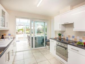 a kitchen with white cabinets and a view of a pool at Flower Pots House - Uk39782 in Paignton