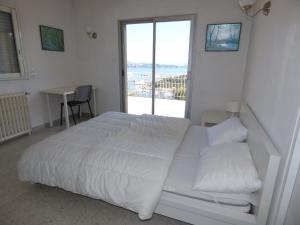 een witte slaapkamer met een bed en een raam bij Haut de villa, pleine vue mer in Saint-Mandrier-sur-Mer