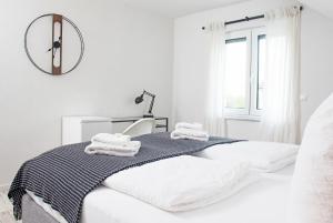 a white bedroom with a bed and a clock on the wall at BlackNCozy - Design Appartement mit Boxspringbett und Balkon in Lörrach