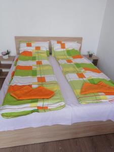 uma cama com lençóis e almofadas laranja e verde em Very good location em Hunedoara