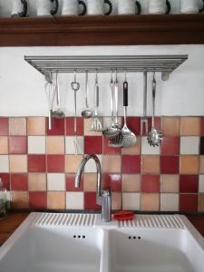 - un évier de cuisine avec des ustensiles suspendus à un portant dans l'établissement Gîte La maison rose, à Hamois