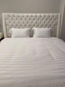 1 cama blanca grande con colcha y almohadas blancas en Minimalist Cozy Apartment by MESA, en Nagoya