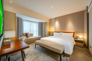 een hotelkamer met een groot wit bed en een bureau bij Holiday Inn Shanghai Huaxia, an IHG Hotel - overlooking city scenery at Sky View Restaurant in Shanghai