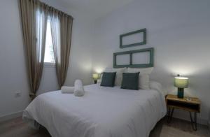 Un dormitorio con una cama blanca grande y una ventana en El Mirador de El Puerto, en El Puerto de Santa María