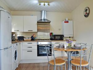 a kitchen with white appliances and a table with chairs at The Meadow Flat in Shanklin