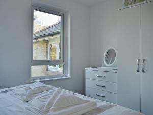 a white bedroom with a bed and a window at The Meadow Flat in Shanklin