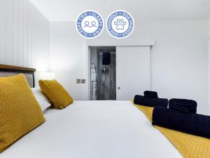 - une chambre avec un grand lit blanc et des oreillers jaunes dans l'établissement Driftwood Boutique Guest House, à Rhosneigr