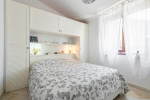 een witte slaapkamer met een bed en een raam bij Attico il Mandorleto in Villasimius