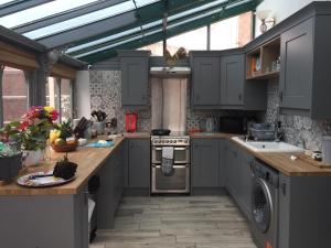 cocina con armarios grises y horno con fogones en Willow Guest House, en Norwich