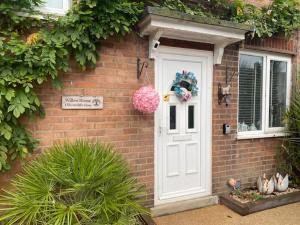 uma casa de tijolos com uma porta branca e uma janela em Willow Guest House em Norwich