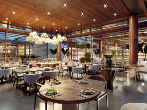 a restaurant with tables and chairs and chandeliers at Île de Pipa com Hidromassagem in Pipa