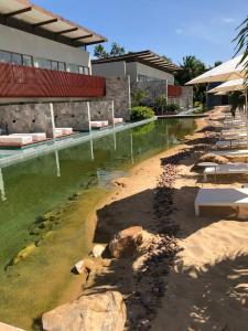 a pool of water with rocks in front of a building at Île de Pipa com Hidromassagem in Pipa