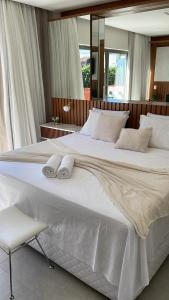 a large white bed with white pillows and a chair at Île de Pipa com Hidromassagem in Pipa