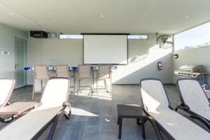Habitación con sillas y pantalla de proyección en Aquaville Dorado Moderna A Studio 7, en Dorado