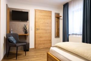 a bedroom with a bed and a chair and a door at Landgasthof Zum Schloss in Birgland