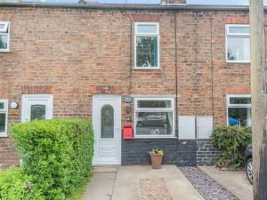 a brick building with a white door and windows at Comfy Kozy Cottage in Louth