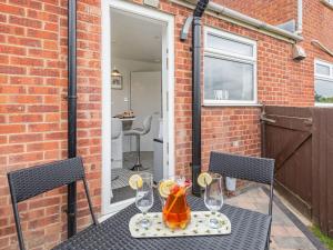 a table with two wine glasses on a patio at Comfy Kozy Cottage in Louth