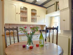 a table with a bottle of wine and flowers on it at Rebeccas Cottage in Ashby Saint Ledgers