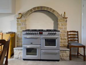 cocina con horno y pared de piedra en The Mill Cottage en Ault Hucknall