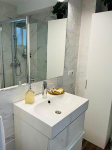 La salle de bains blanche est pourvue d'un lavabo et d'un miroir. dans l'établissement Petit apartment LOS REMEDIOS, à Séville
