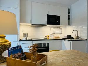 セビリアにあるPetit apartment LOS REMEDIOSの白いキャビネットと木製テーブル付きのキッチン