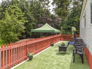 a patio with a fence and a green umbrella at Tranquillity Lodge in Annbank